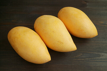 Row of Fresh Ripe Mango Fruits on Black Wooden Table