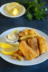 Bastoncini di pesce fritti con patatine fritte. Fish and chips britannico su sfondo grigio.