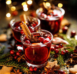 Delicious Christmas drink, hot mulled wine with citrus, spices and cranberries on on a decorated festive table close up view