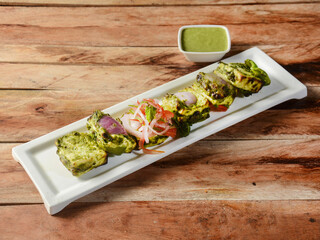 Pahadi Paneer tikka is a delicious starter made with Indian Cottage Cheese marinated, served over a rustic wooden background, selective focus