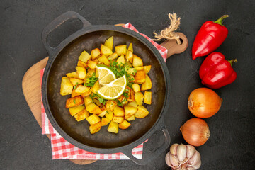 top view fried potatoes inside pan with lemon and vegetables on a dark background cuisine meal food color