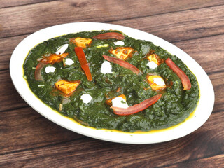 Palak Paneer Curry made up of spinach and cottage cheese, helathy indian traditional dish, served over a rustic wooden background, selective focus