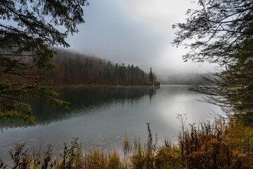 idyllic mountain lake in autumn with dense fog