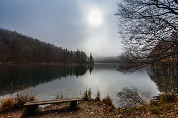 beautiful idyllic mountain lake in autumn with fog and sun