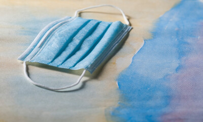 mascarilla azul quirúrgica sobre papel de acuarela artístico amarillo y azul haciendo aguas