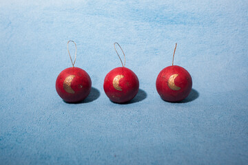3 bolas rojas con lunas doradas de adorno de árbol de navidad sobre tejido suave azul claro