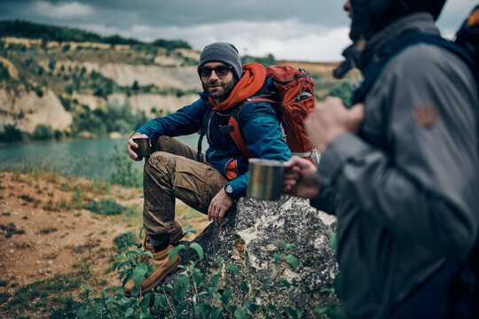 Two Men In Nature Taking A Break From Hiking. They Refreshing And Drinking Hot Tea.