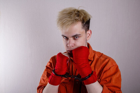 A Teenage Athlete In Handcuffs And Boxing Bandages On A Gray Background.concept: Athletes Are Hooligans. Juvenile Delinquent, Criminal Liability Of Minors. Members Of Youth Criminal Groups And Gangs.