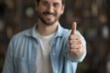 Crop close up blurred view of happy male client or customer show thumb up recommend good quality...