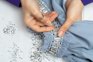 Embroidery process close up, tailor embellished blue dress with crystals
