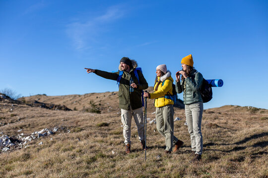 A group of friends is hiking at the top of the mountain and enjoying the fresh air. 