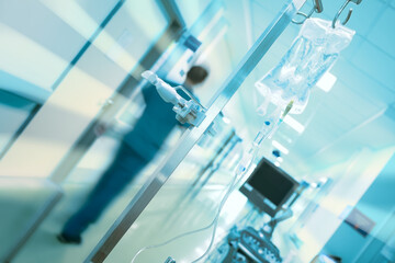 Concept of rescue emergency care. Blurred in motion figure of medical doctor, intravenous drip on the pole and ultrasonic diagnostic apparatus in hospital hallway