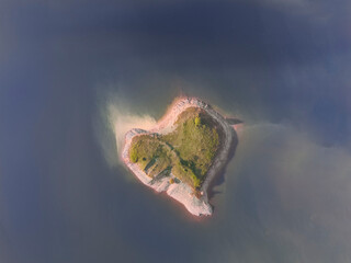 A heart-shaped island in the middle of a lake during a lovely sunset.