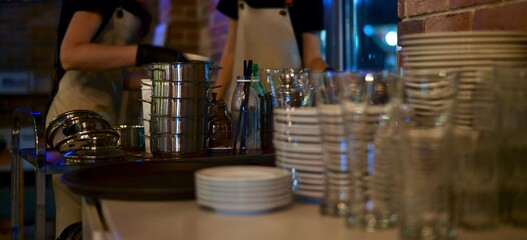 The working staff of the restaurant cafe in uniform in aprons, sort stacks of utensils in gloves in the background.