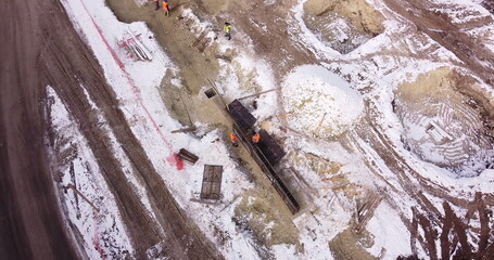 Engineers work with metal constructions while building a house. Aerial Flight Over a New Constructions Development Site. Top Down View at Contractors in Safety Hats.