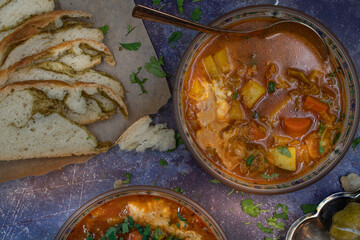 Vegan or vegetarian soup in ceramic bowls with herbed bread on gray table