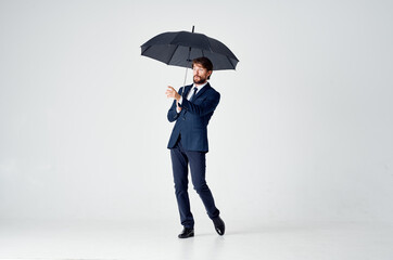 elegant gentleman with a dark umbrella on a light background and a classic suit