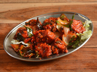 Paneer Manchurian is Indo Chinese cuisine dish, Paneer cubes tossed with tomatoes, onions, spring onions, sesame seeds and soy sauce. served over a rustic wooden background, selective focus