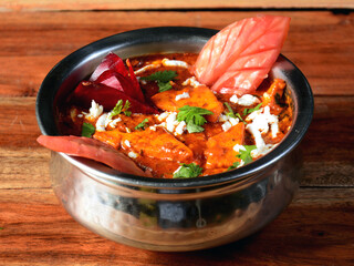 Paneer lababdar, is a famous indian dish, served over a rustic wooden background, selective focus