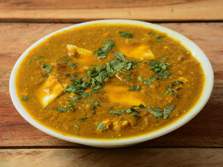 Paneer Masala or Cheese Cottage Curry, is a famous indian dish, served over a rustic wooden background, selective focus