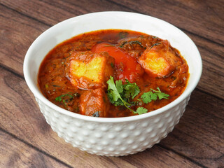 Paneer Masala or Cheese Cottage Curry, is a famous indian dish, served over a rustic wooden background, selective focus