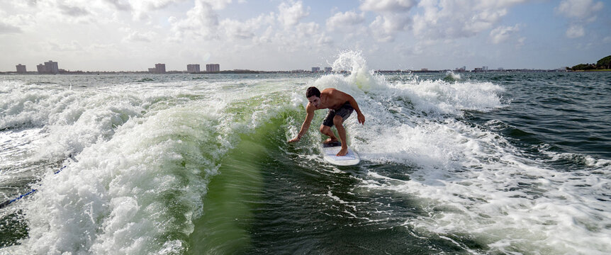 Man surfing skims the water with hand over a green wave