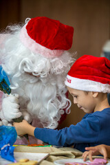 Little boy decorating Christmas biscuits and gingerbread cookies in kitchen together with Santa Claus. Kids cooking class. Merry Christmas and happy holidays