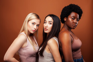 young pretty asian, caucasian, afro woman posing cheerful together on brown background, lifestyle diverse nationality people concept