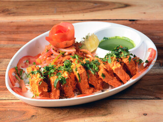Paneer Tikka Kabab is an Indian dish made from chunks of cottage cheese marinated in spices and grilled in a tandoor. served over a rustic wooden background, selective focus
