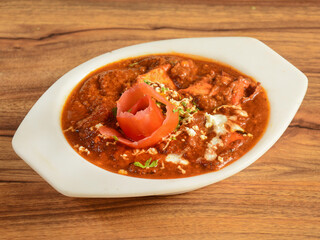 Paneer Tikka Masala is a famous indian dish, served over a rustic wooden background, selective focus