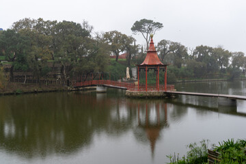 view of a meditative lake and bridge with gazebo in the Buddha Eden Garden in Portugal