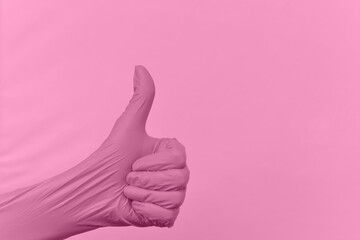 Gesture of a hand thumb up in a rubber glove color pink prism against a raised tinted background...