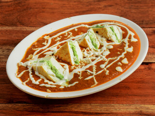 Paneer pasanda, is a famous indian dish, served over a rustic wooden background, selective focus