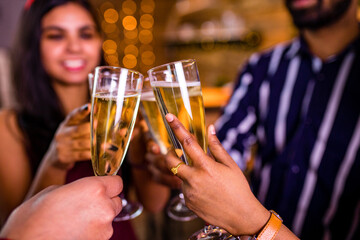 group of four indian friends cheering with champagne flutes and looking happy while having party on the kitchen at stay home quarantine corona virus outbreak party
