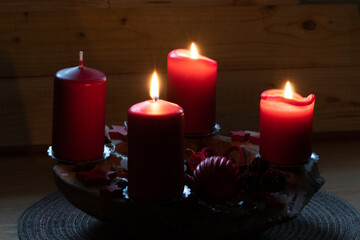 Rote brennende Kerzen auf einem Adventsgesteck. Es ist der dritte Advent. Bald ist Weihnachten.