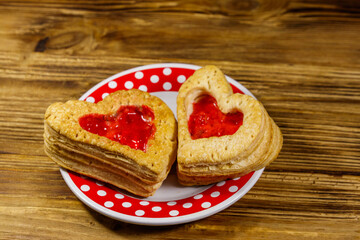 Heart shaped puff cookies with jam on a wooden table. Dessert on Valentine`s Day