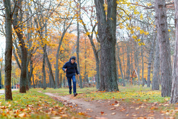 Fototapeta premium a boy running through the park and enjoys autumn, beautiful nature with yellow leaves