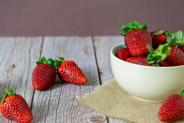 Strawberries in a bowl on top of a wooden table