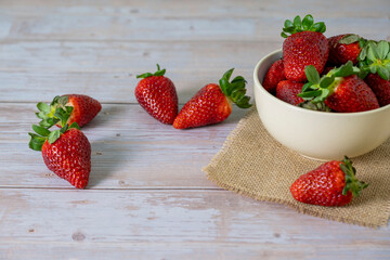 Strawberries in a bowl on top of a wooden table