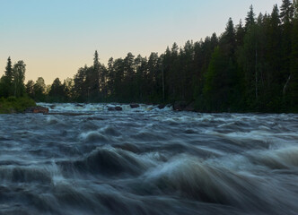 Kengis rapids on Torne river in Northern Sweden near border with Finland with midnight sun in early morning in July 2019.