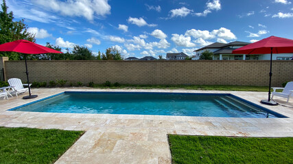A relaxing backyard swimming pool with red umbrellas