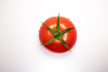 Close up view of tomato isolated on a white background with water drops on surface green stem top side. Space for copy
