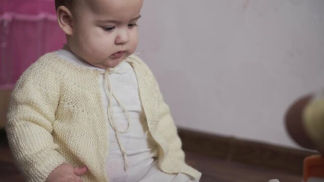 infant, childhood concept - happy funny playfull toddler kid 8 month baby girl learn to sit singly play in playroom. smiling chubby active awake newborn in white crawl on knees floor indoors at home