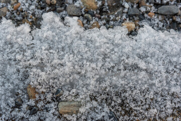 Icy lake shore with rocks pebbles and ice forming on the edge. Taken in fall autumn in northern Canada. Beautiful background graphic resource shot.