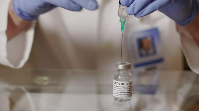 As per the instructions from the manufacturer a doctor healthcare worker or medical technician dilutes the COVID19 vaccine and gently shakes the vial to ready it for the immunization process.