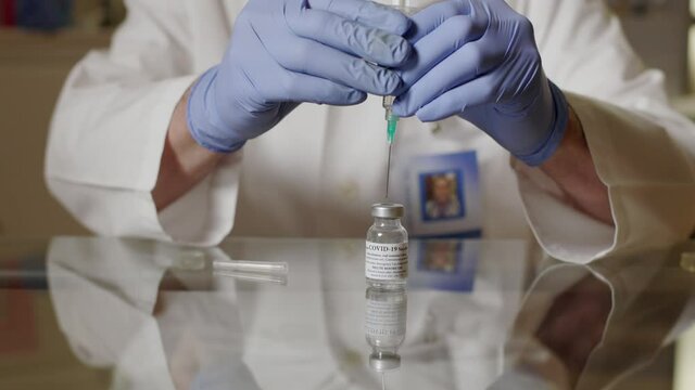 A doctor healthcare worker or medical technician per the instructions from the manufacturer dilutes the COVID19 vaccine and gently shakes the vial to ready it for the immunization process.