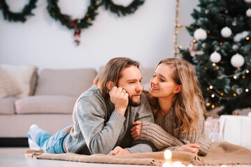 Happy couple lying on the floor of their house decorated for christmas