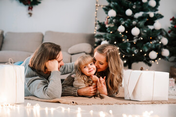 Happy family with daughter lying on the floor in room decorated for the Christmas holidays