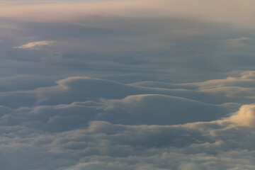 Calming and serene clouds from above with slight sunshine tones on the tops. Heavenly shining cloud in the sky background, wallpaper, wall art beautiful.
