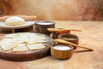 front view raw dough slices with flour and seasonings on the cream desk dish cuisine pasta